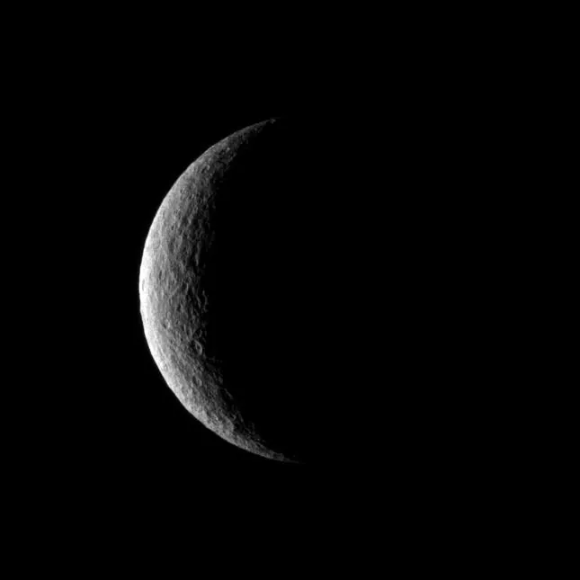 Crescent view of the cratered moon Rhea.